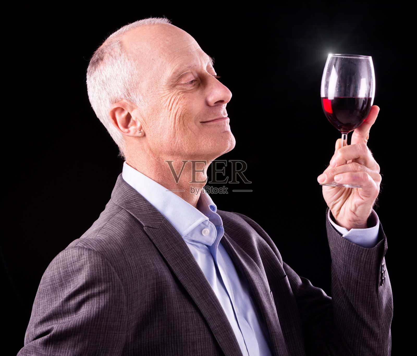 成熟的男人举起红酒，微笑着欣赏照片摄影图片