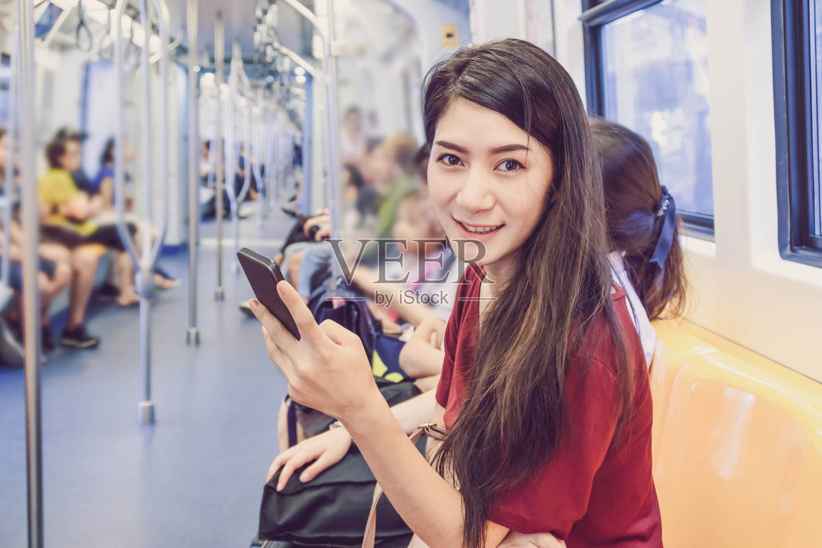 亚洲女性乘客休闲套装使用智能手机在BTS轻轨或捷运地铁在大城市旅行，生活方式和交通理念照片摄影图片