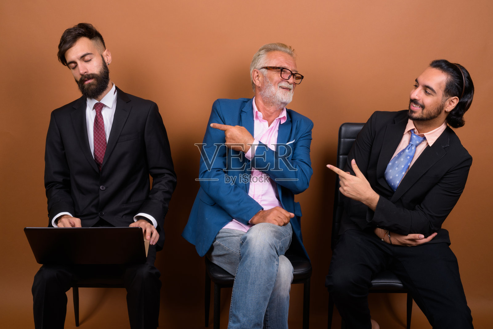 工作室拍摄的多民族的三个留着胡子的商人在有色背景下一起等待采访照片摄影图片