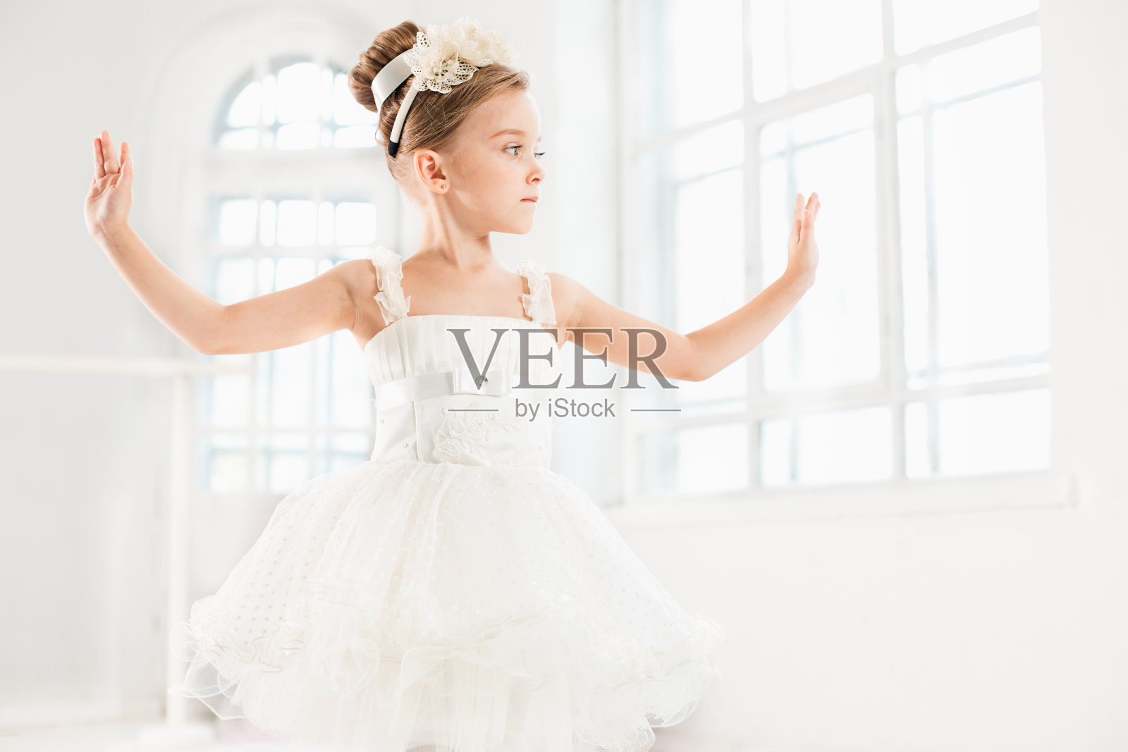 穿着芭蕾舞裙的小芭蕾舞女。可爱的孩子在一个白色的工作室里跳古典芭蕾照片摄影图片