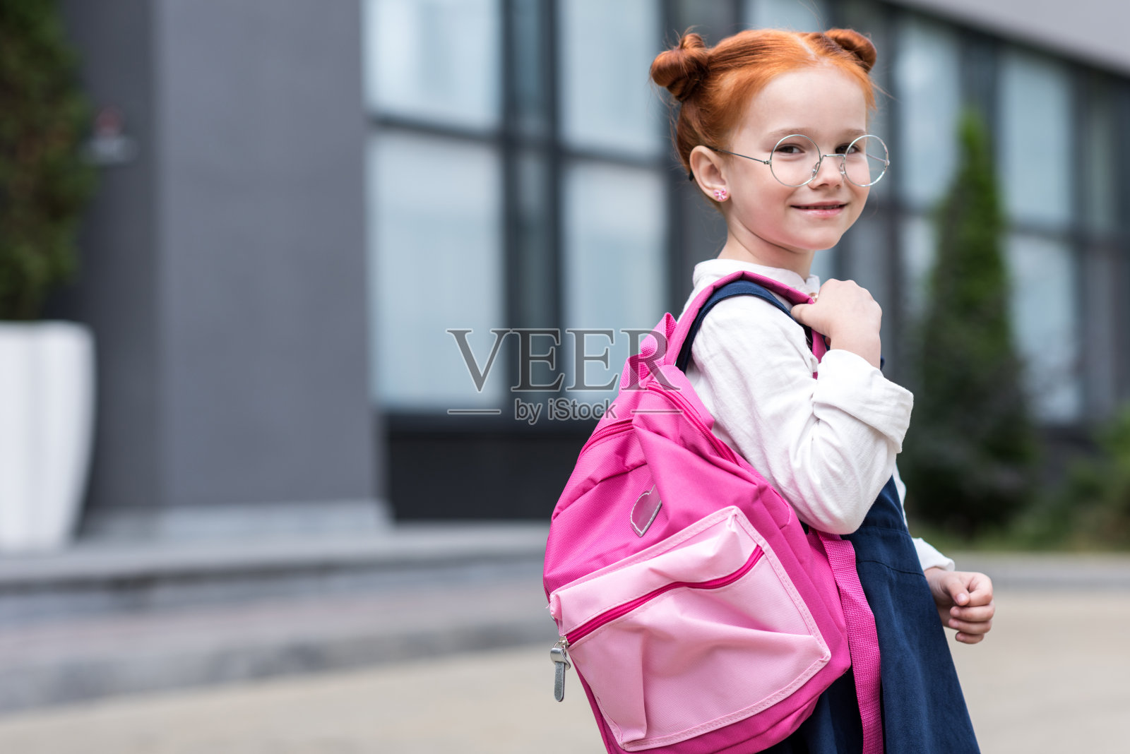 可爱的红发小女生戴着眼镜，背着书包，对着镜头微笑照片摄影图片