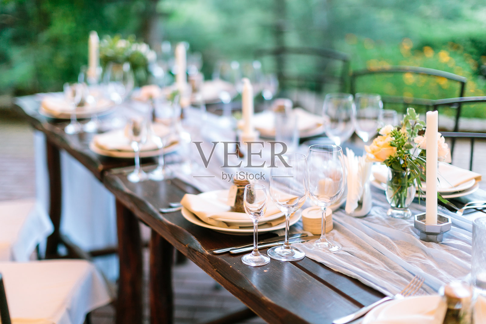 盛宴，晚餐，传统观念。长长的橡木桌子用于庆祝银器，盘子和透明的耀眼的眼镜，鲜花和蜡烛在有趣的八角形的持有者照片摄影图片