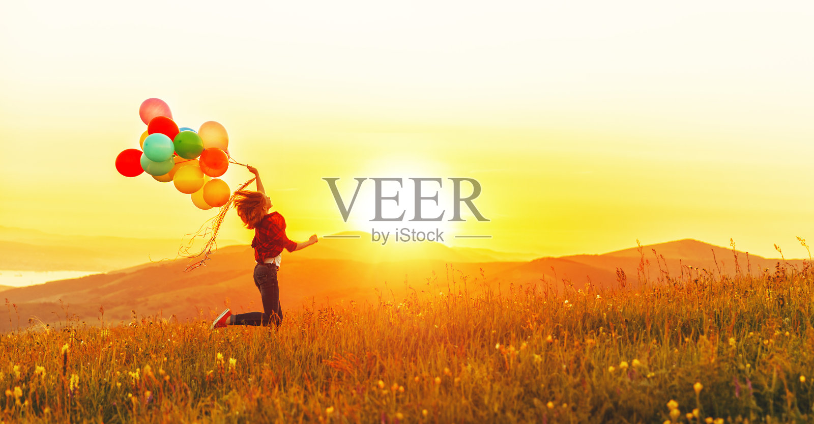 快乐快乐的女孩与气球在夏季日落草地上奔跑照片摄影图片