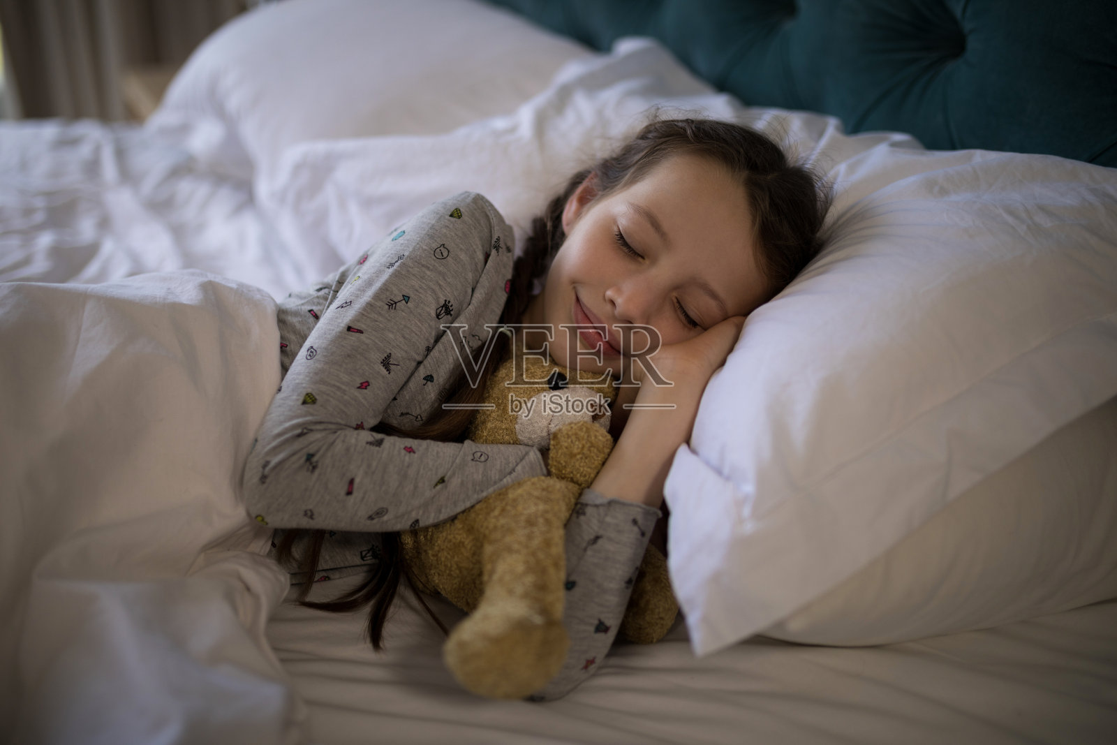 女孩睡在床上，卧室里有泰迪熊照片摄影图片