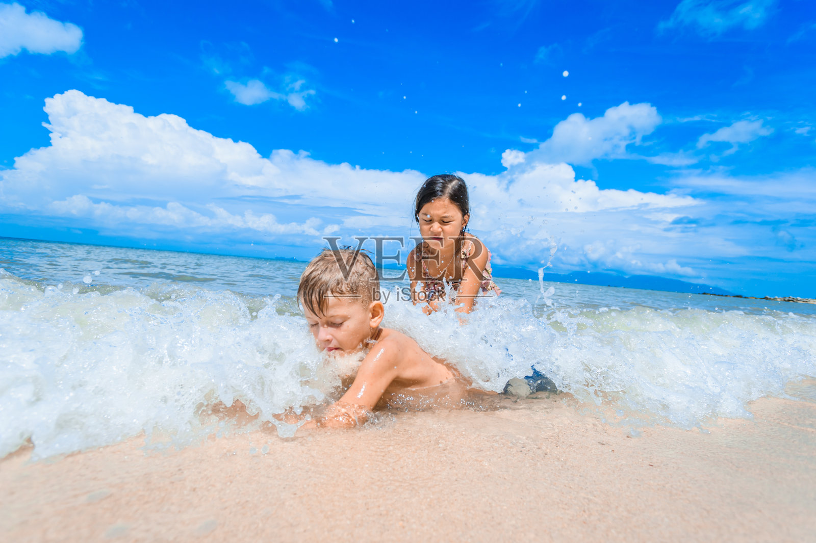 两个孩子在阳光明媚的热带海滩上玩照片摄影图片