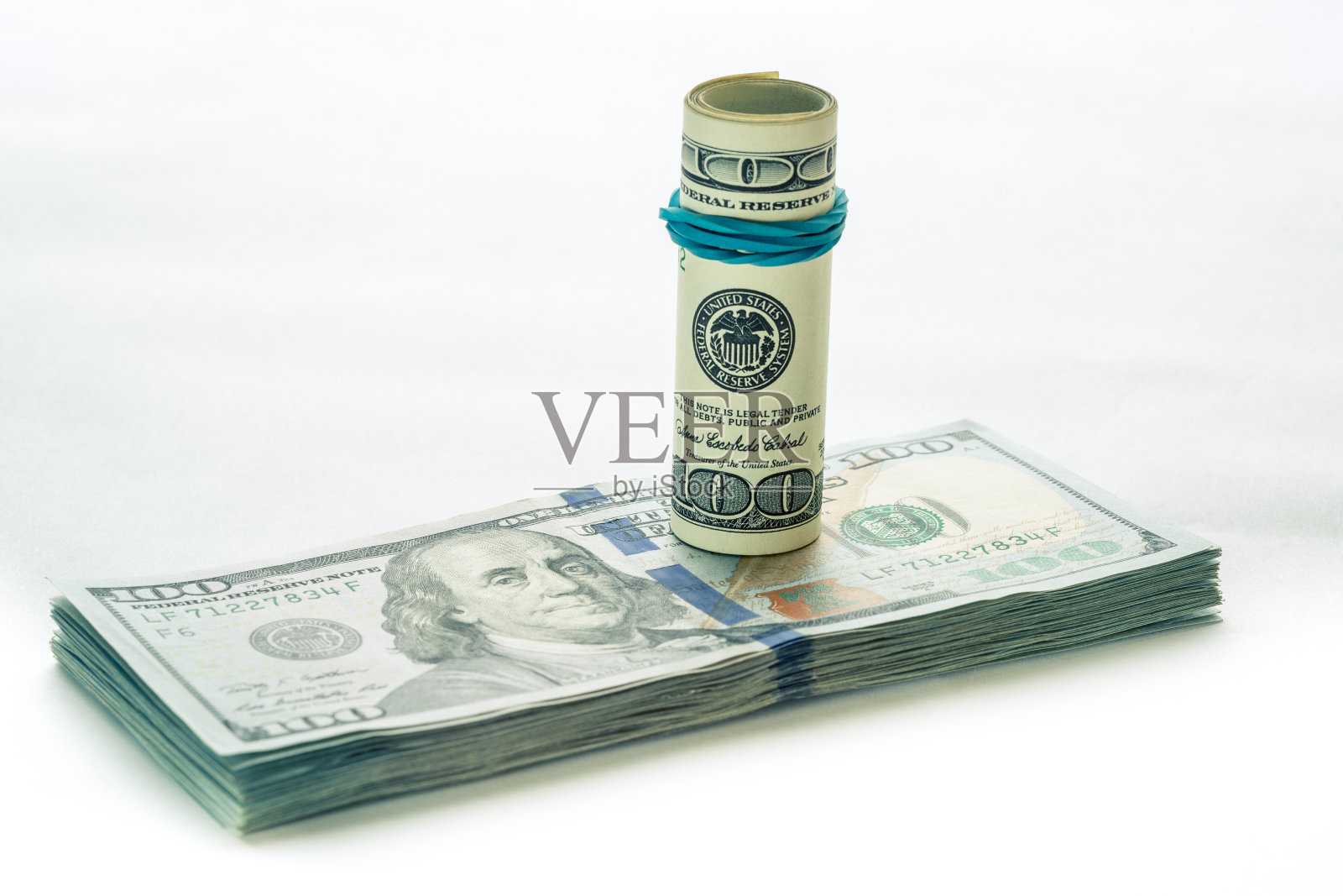 一张盘绕的100元美钞放在另一张倾斜的100元美钞上，孤立在白色背景上照片摄影图片