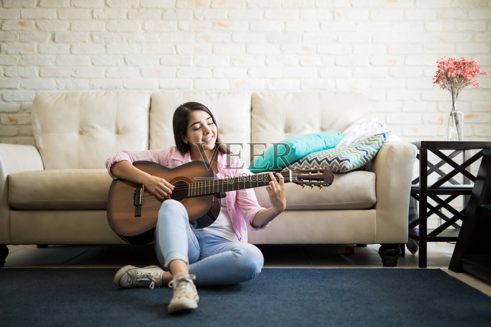 一个女人坐在地板上弹吉他照片摄影图片