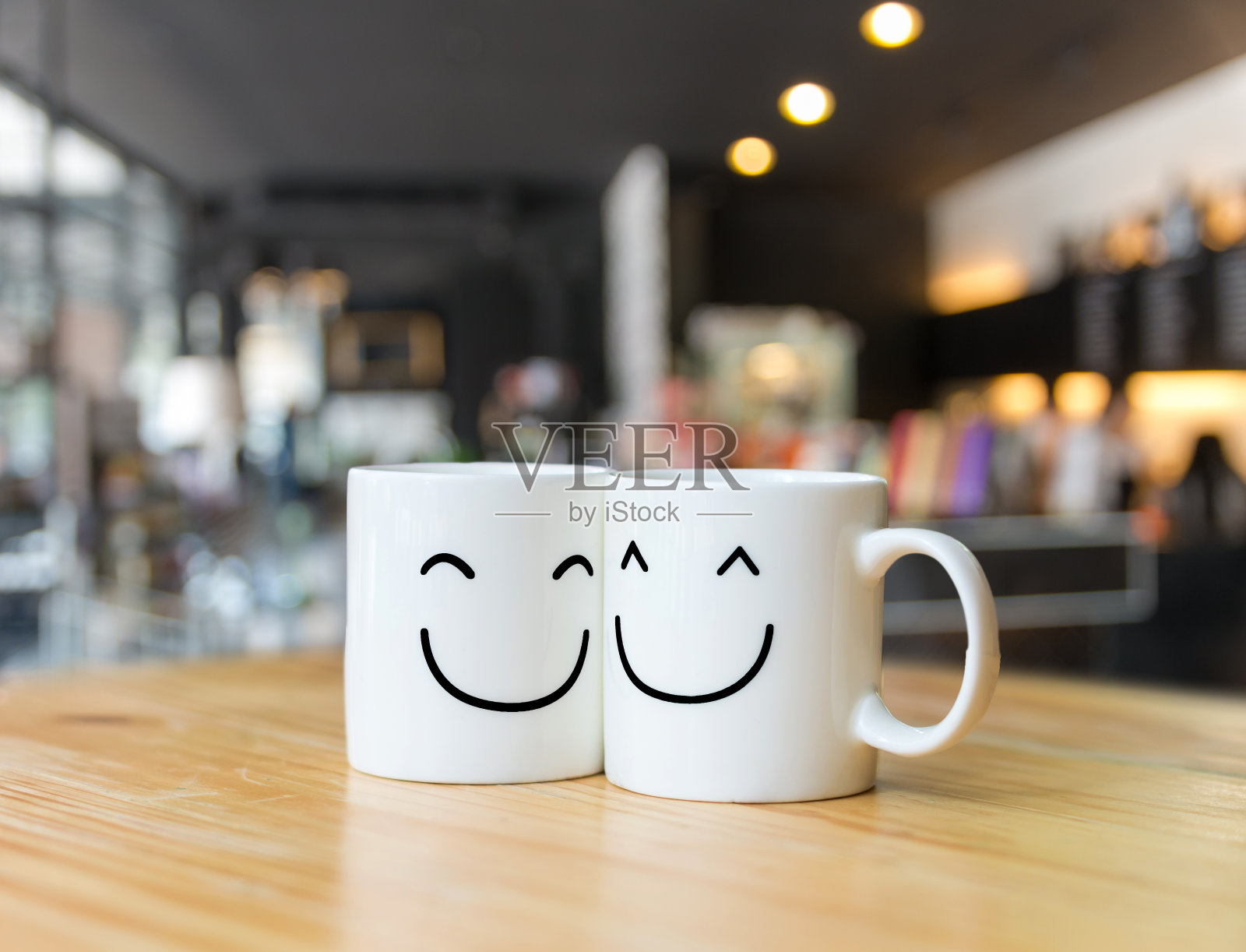 咖啡店里的两个快乐杯子模糊了背景，情人节情人的概念照片摄影图片