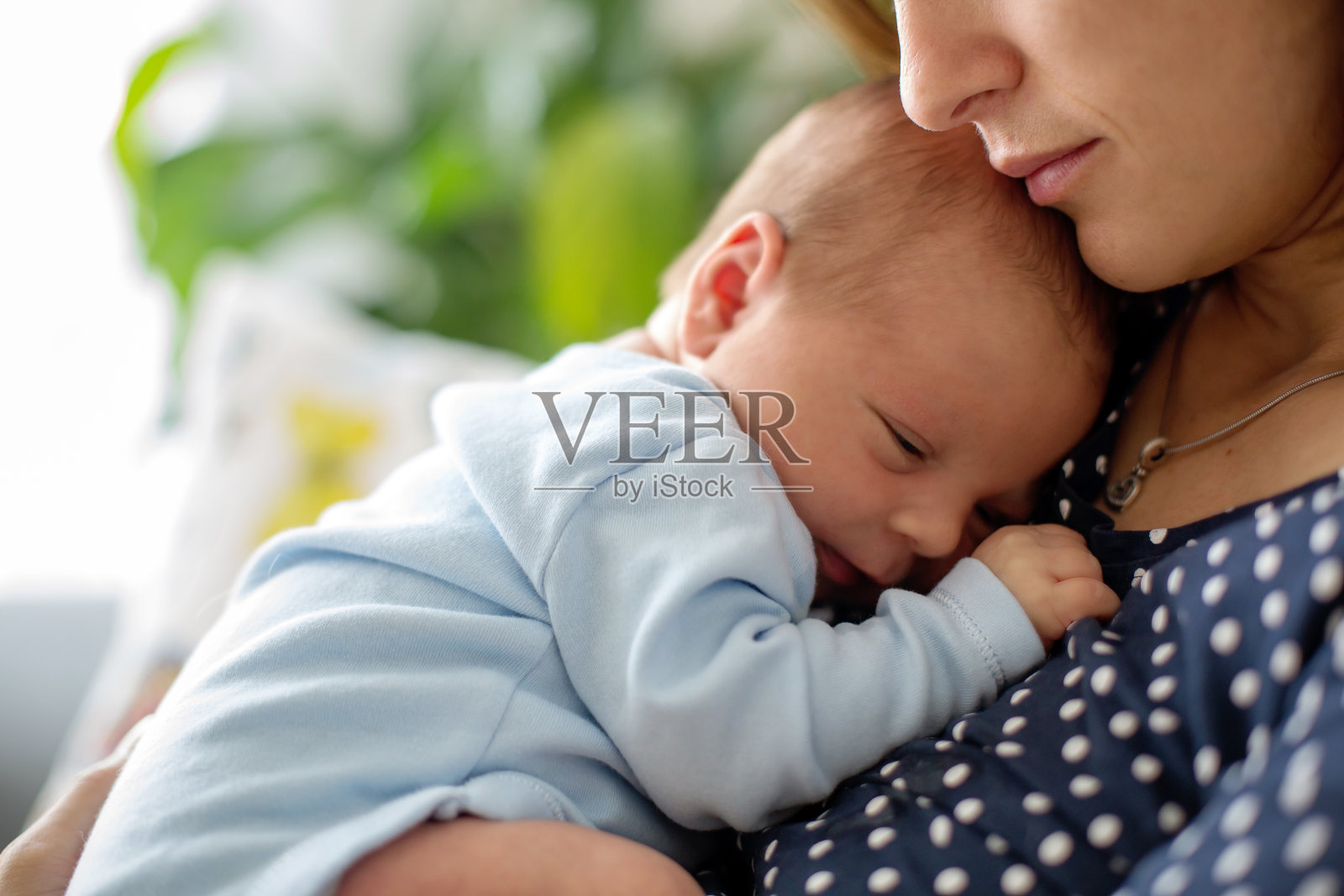 年轻的母亲，温柔地抱着她刚出生的儿子照片摄影图片