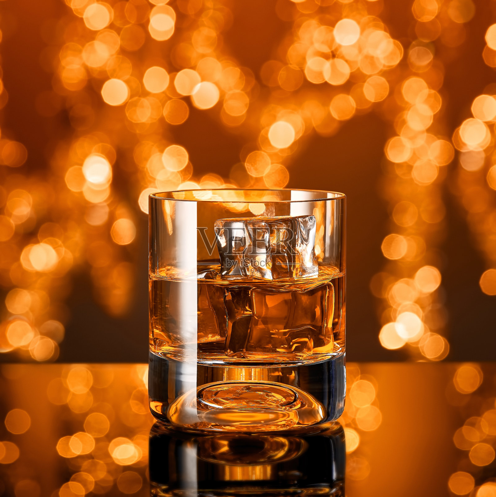 圣诞彩灯前放着一杯加冰块的威士忌照片摄影图片