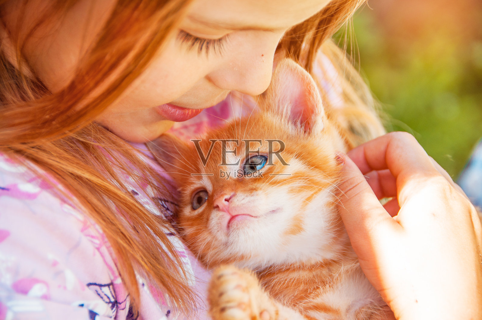 小女孩手里拿着一只红色的小猫。闺中密友。孩子与宠物的互动。照片摄影图片