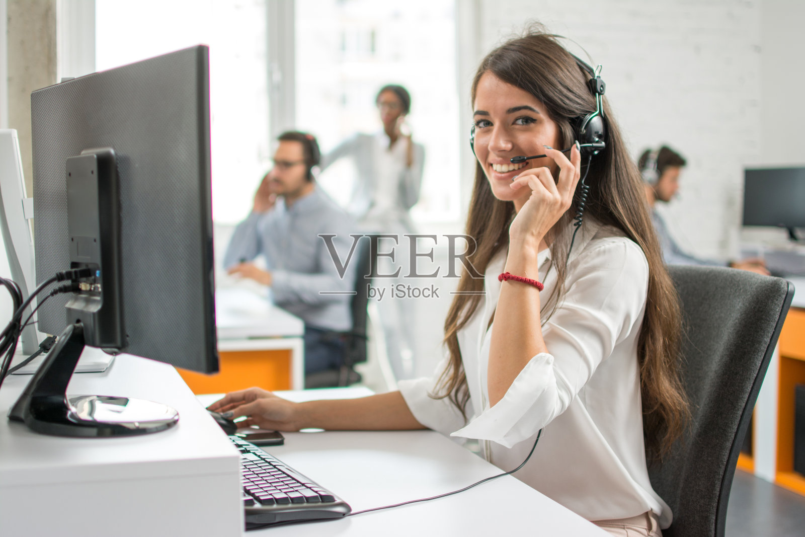 年轻友好的接线员，女代理人与耳机在呼叫中心工作。照片摄影图片