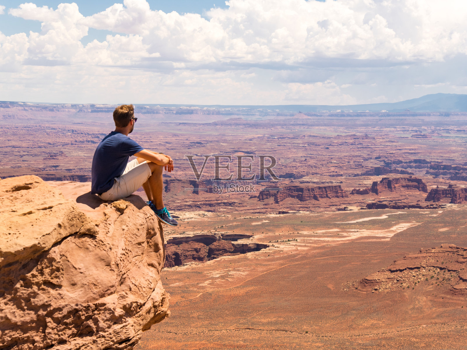 年轻人坐在悬崖上峡谷地国家公园，摩押，犹他州照片摄影图片