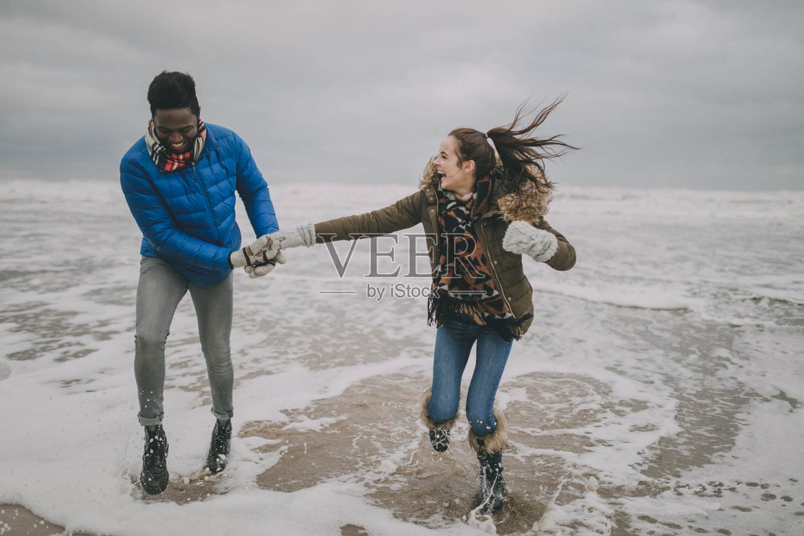 一对年轻夫妇在冬天的海滩上大笑照片摄影图片