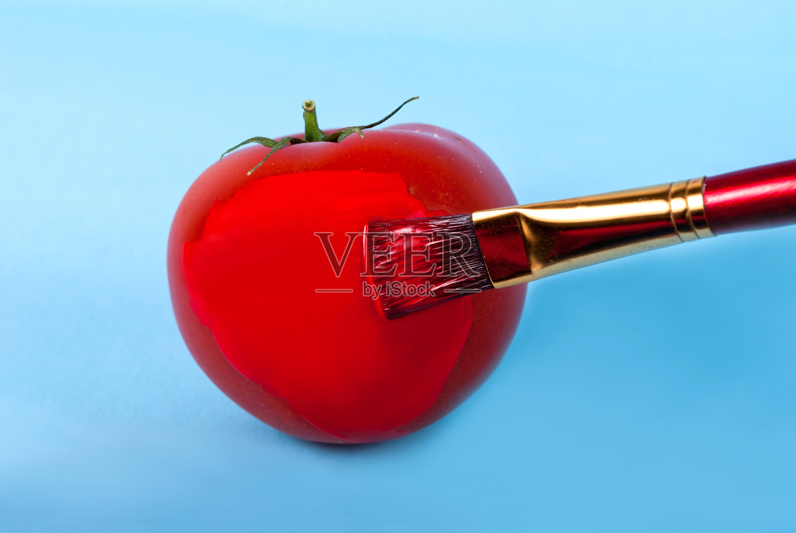 把西红柿刷成鲜红的颜色，在蓝色的背景上，代表坏食物的概念照片摄影图片