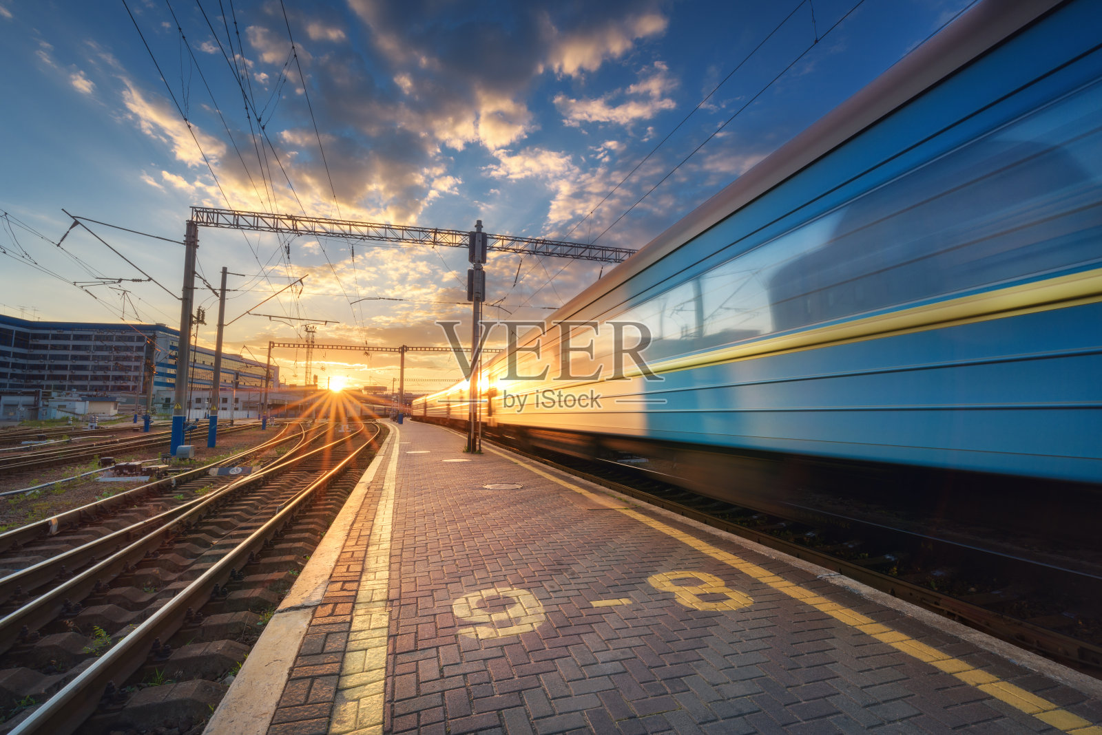 日落时分，欧洲铁路轨道上的高速客运列车。火车站以现代化的通勤列车出发，蓝天伴着白云和阳光。色彩斑斓的工业景观。铁路平台照片摄影图片