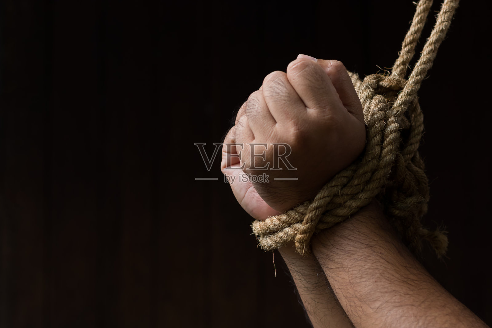 双手被绳子绑在黑色的背景上/自由和人权的丧失照片摄影图片