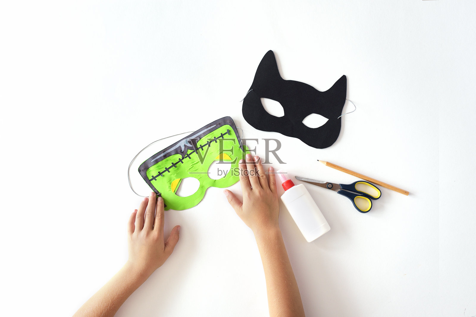 用纸做面具来庆祝万圣节。弗兰肯斯坦的面具和黑猫。照片摄影图片