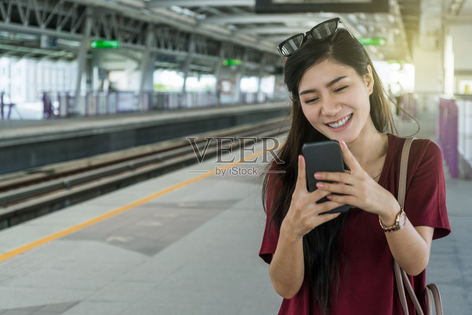 亚洲女性乘客与休闲服装通过智能手机使用社交网络在BTS轻轨或捷运地铁在大城市旅行，生活方式和交通理念照片摄影图片