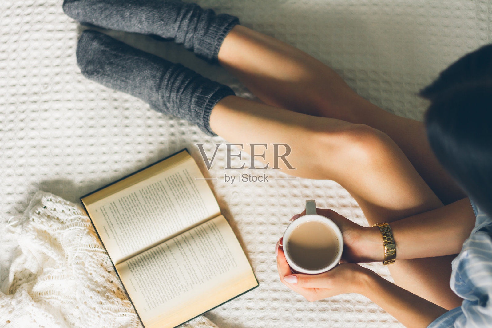 女人躺在床上，用一杯咖啡看书。照片摄影图片