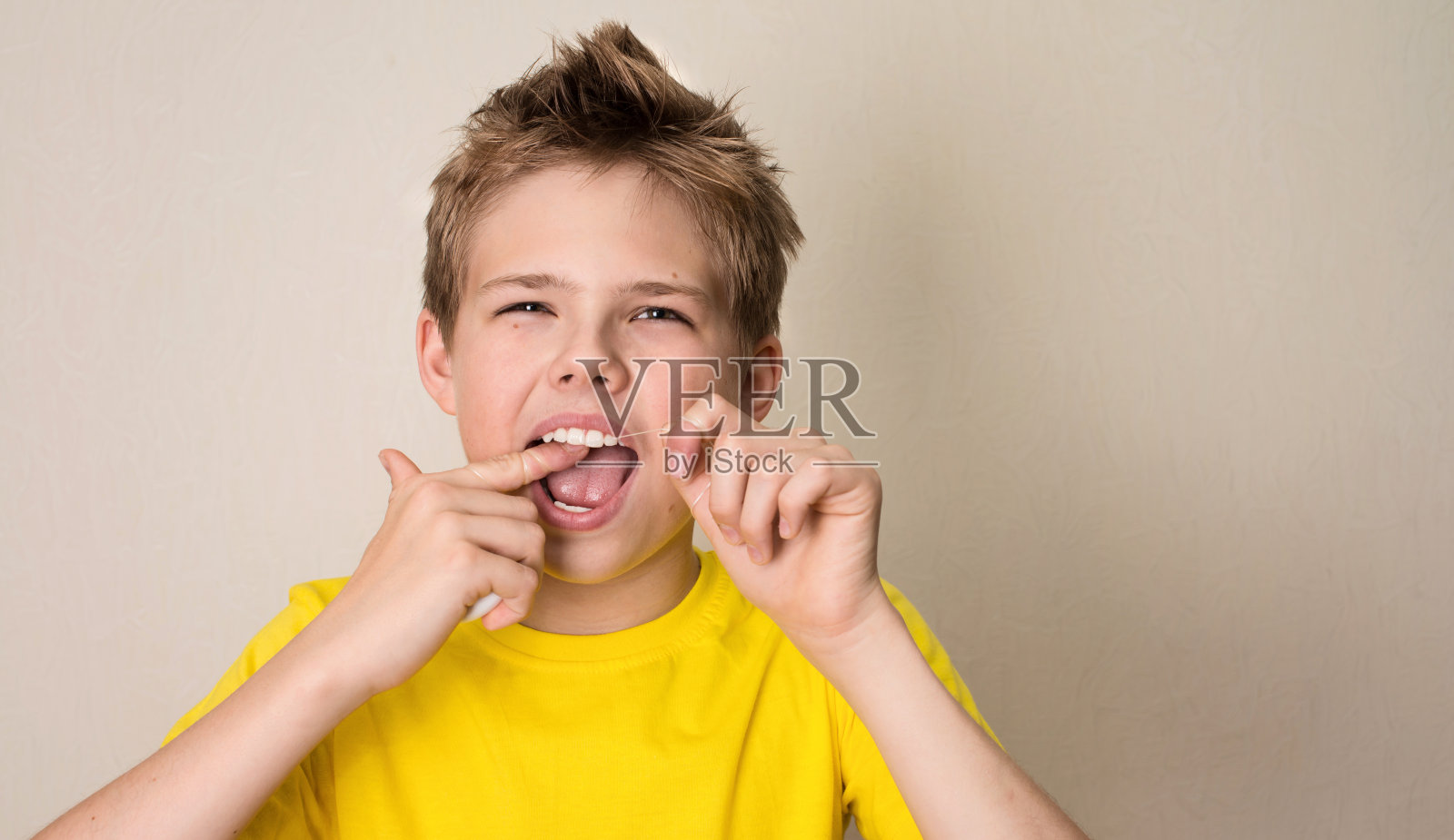男孩用牙线清洁牙齿。特写的十几岁的男孩与牙线孤立。照片摄影图片