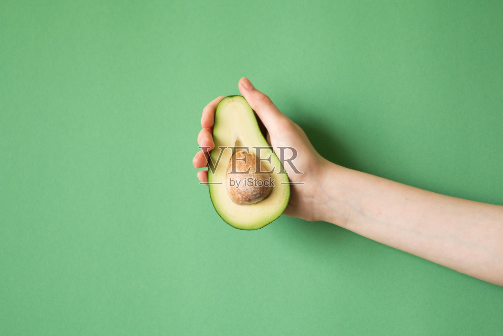 手握牛油果的女人颜色的背景。健康食品的概念照片摄影图片