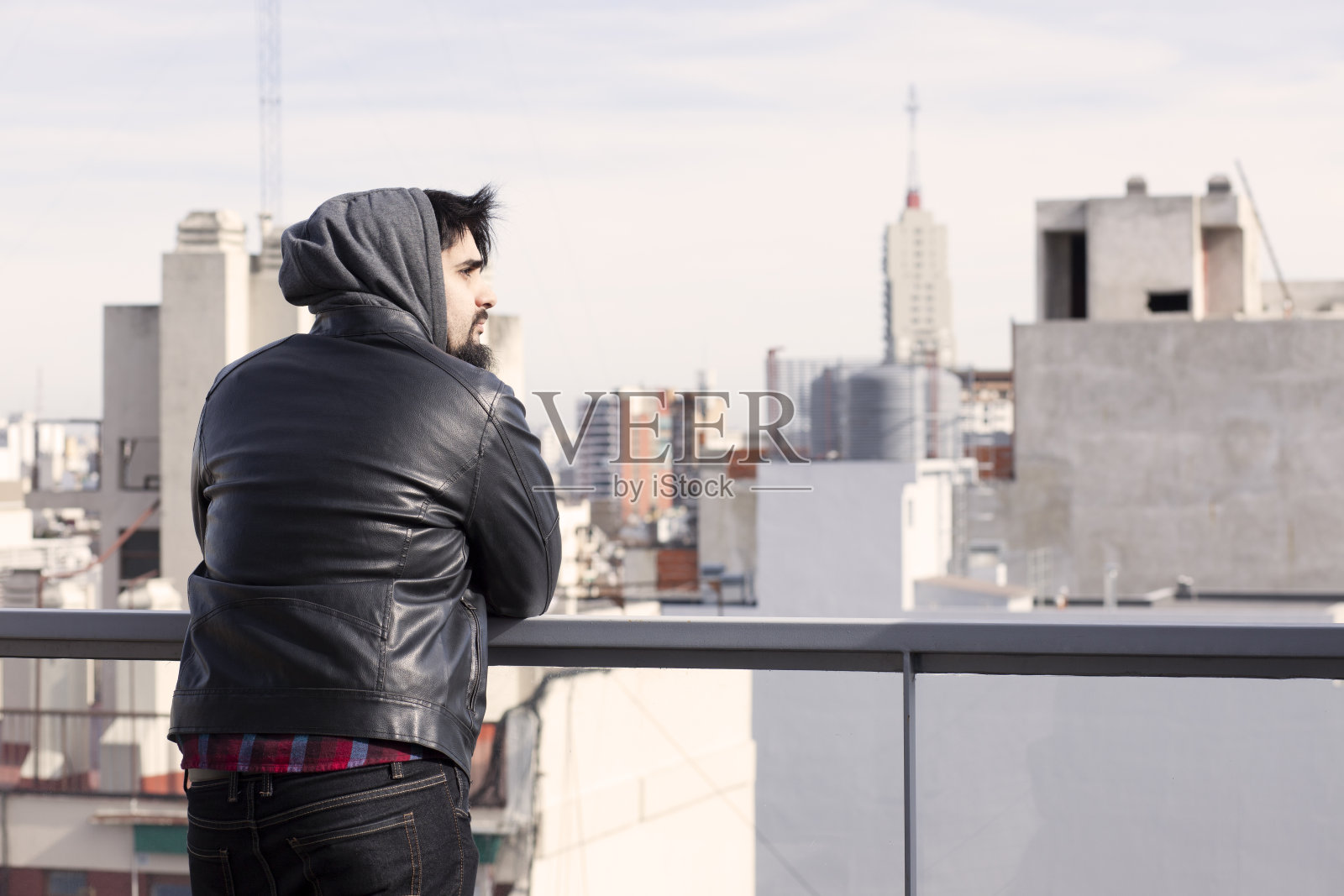 年轻人倚靠在屋顶阳台上照片摄影图片
