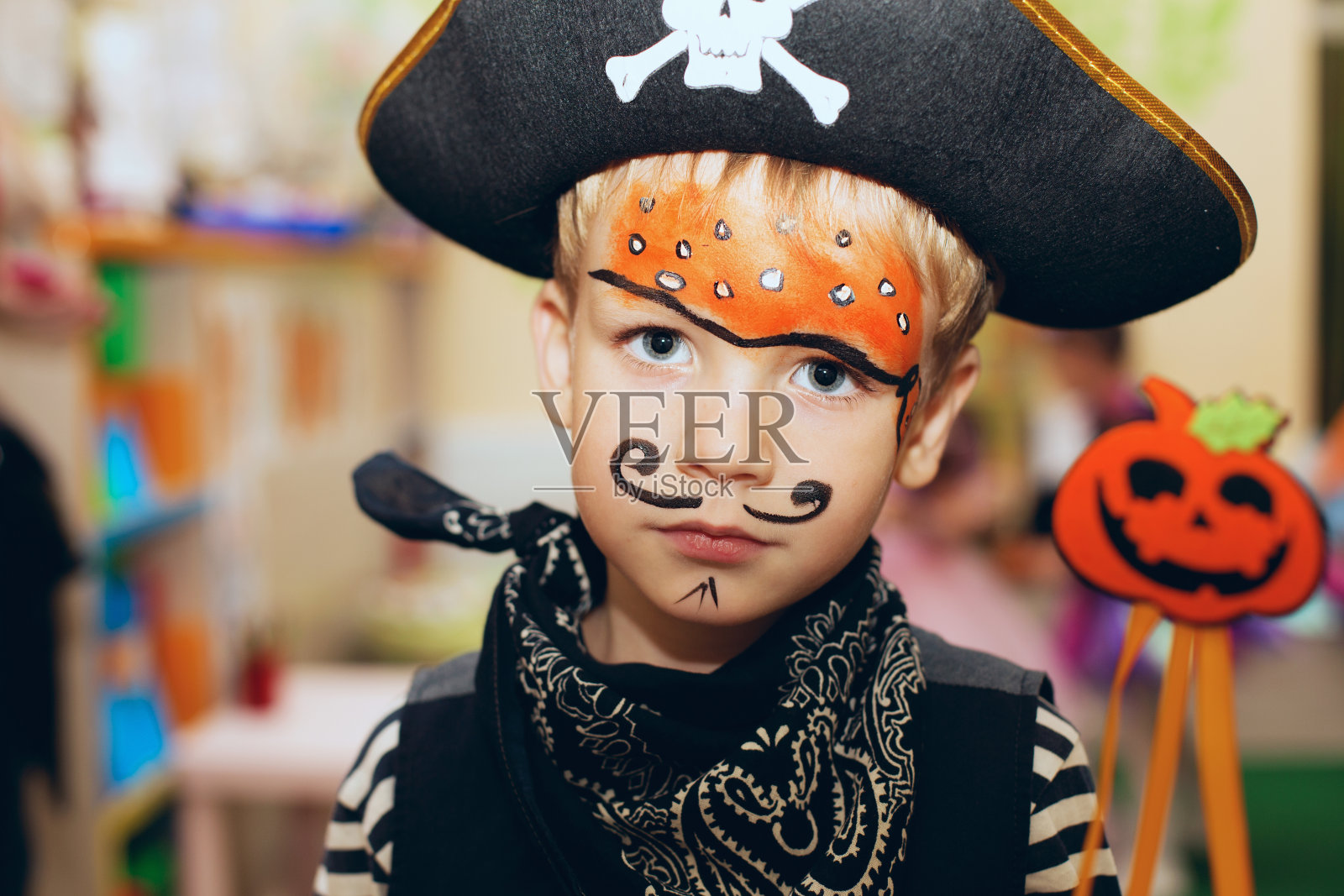 一个小男孩穿着海盗装，脸上画着妆，在万圣节派对上玩得很开心照片摄影图片