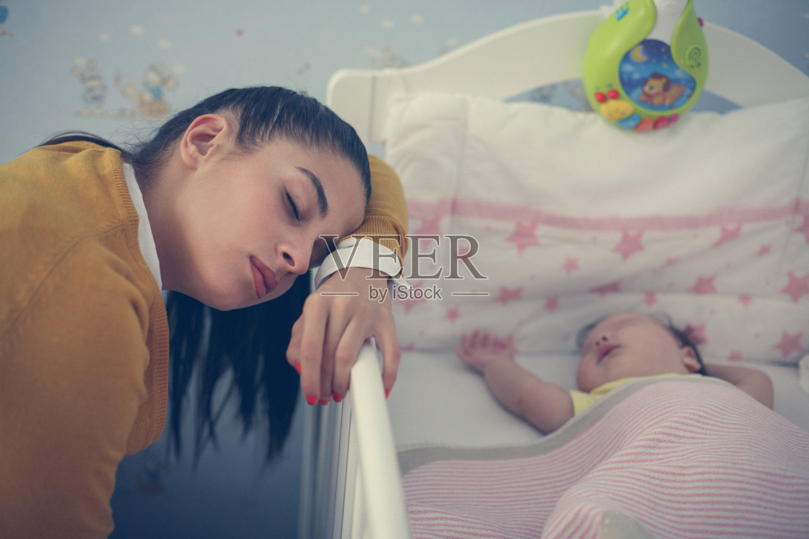 疲惫的妈妈在宝宝旁边做梦。照片摄影图片