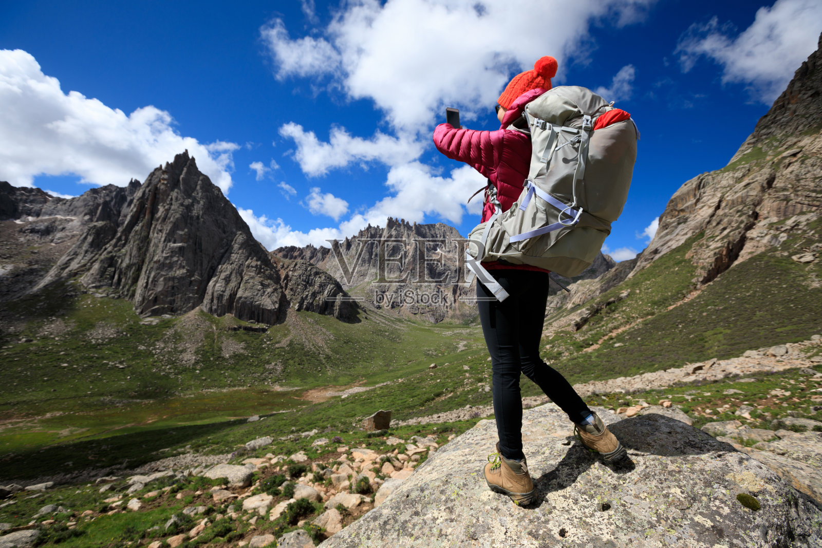 成功的女性徒步旅行者在山顶岩石使用智能手机照片摄影图片
