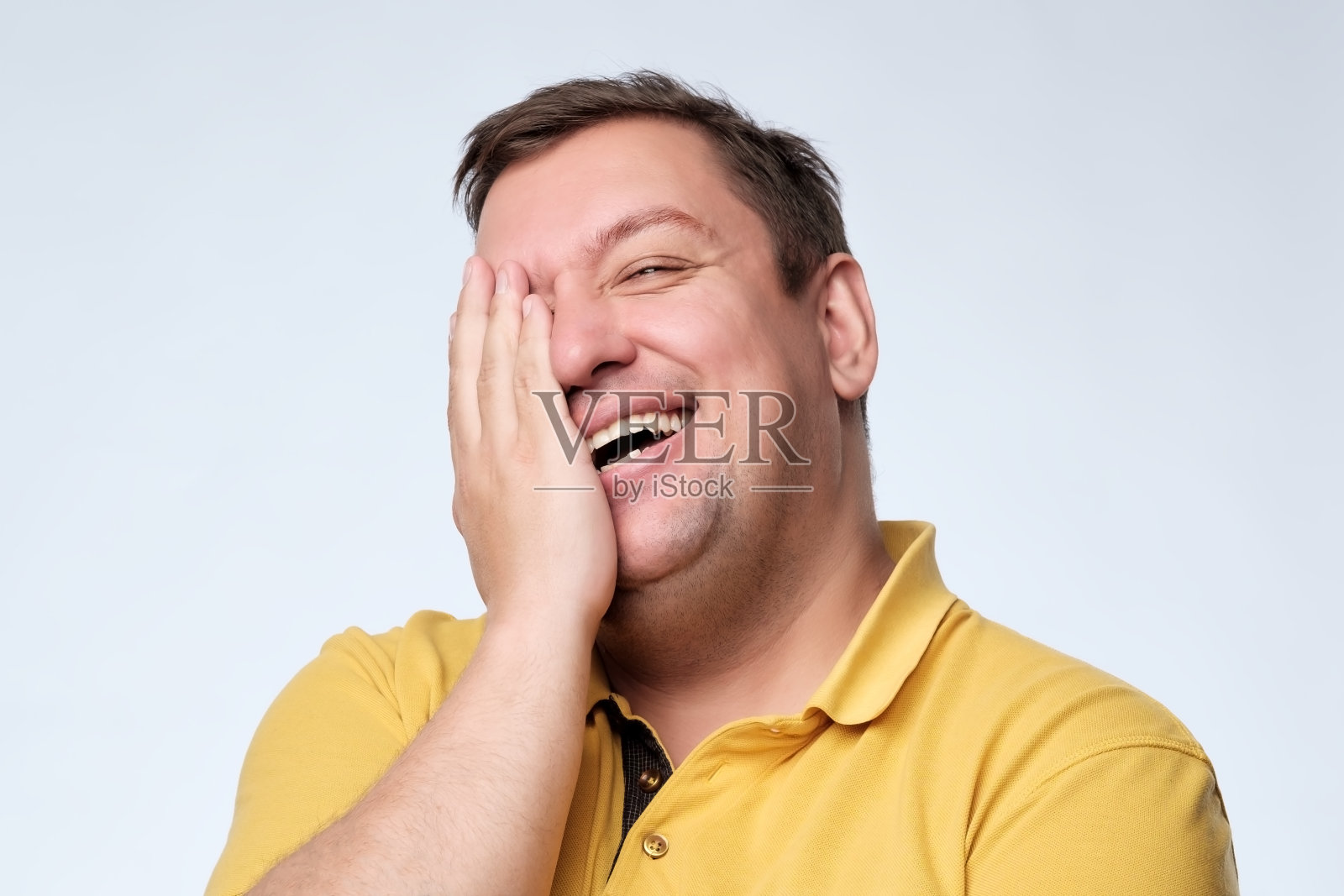 一个白人胖子笑着用手捂着脸。照片摄影图片