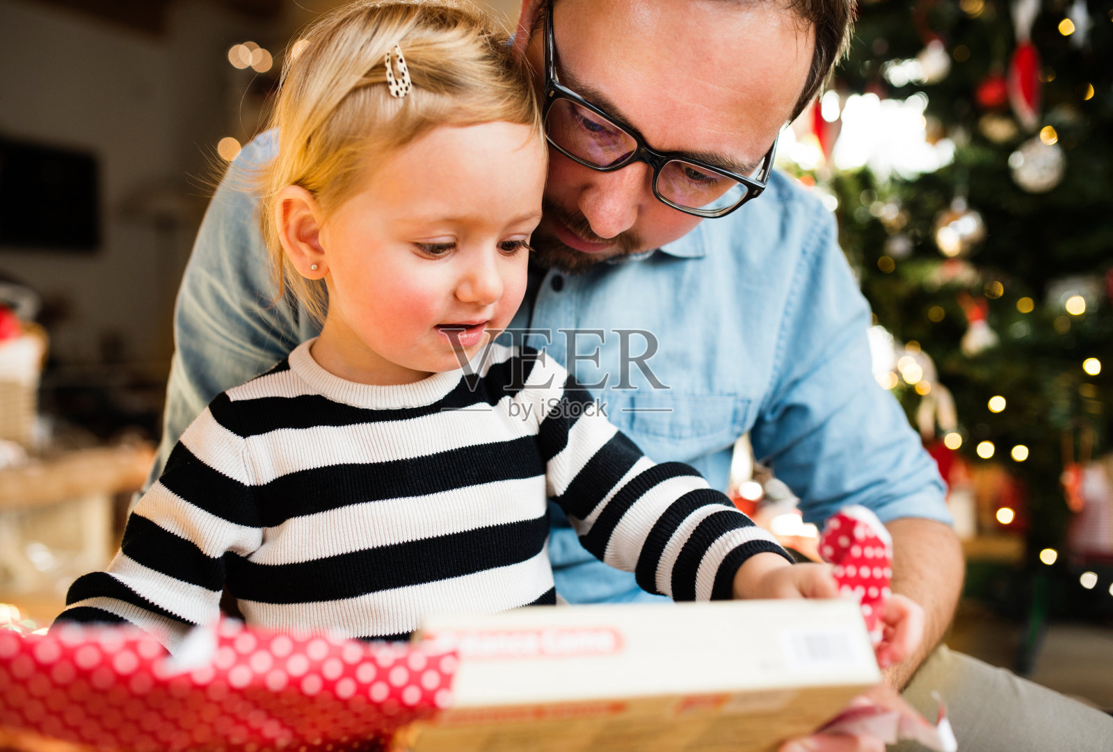 小女孩和她的父亲打开圣诞礼物。照片摄影图片