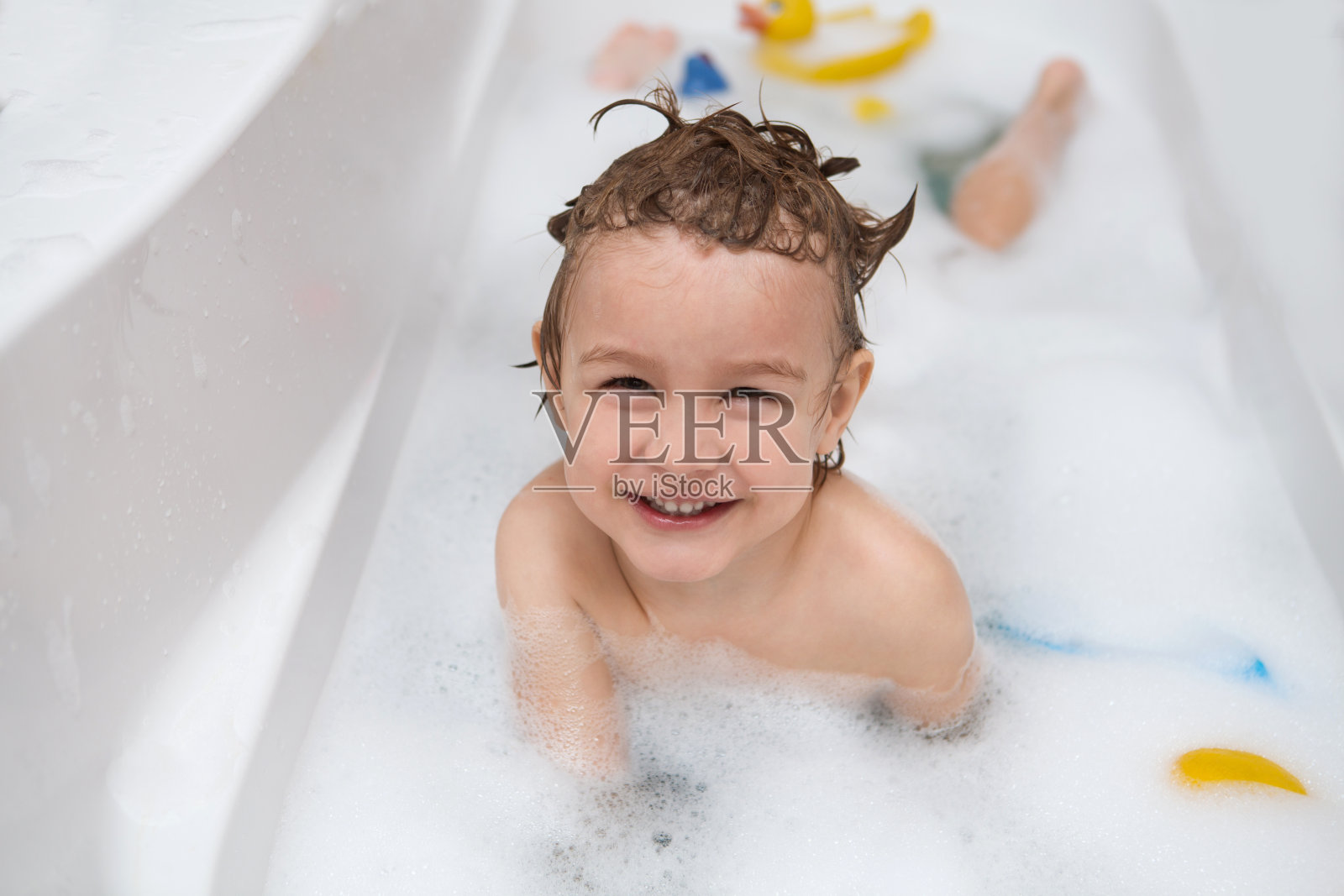 有趣的孩子在浴室里玩水和泡沫。小男孩洗澡。照片摄影图片
