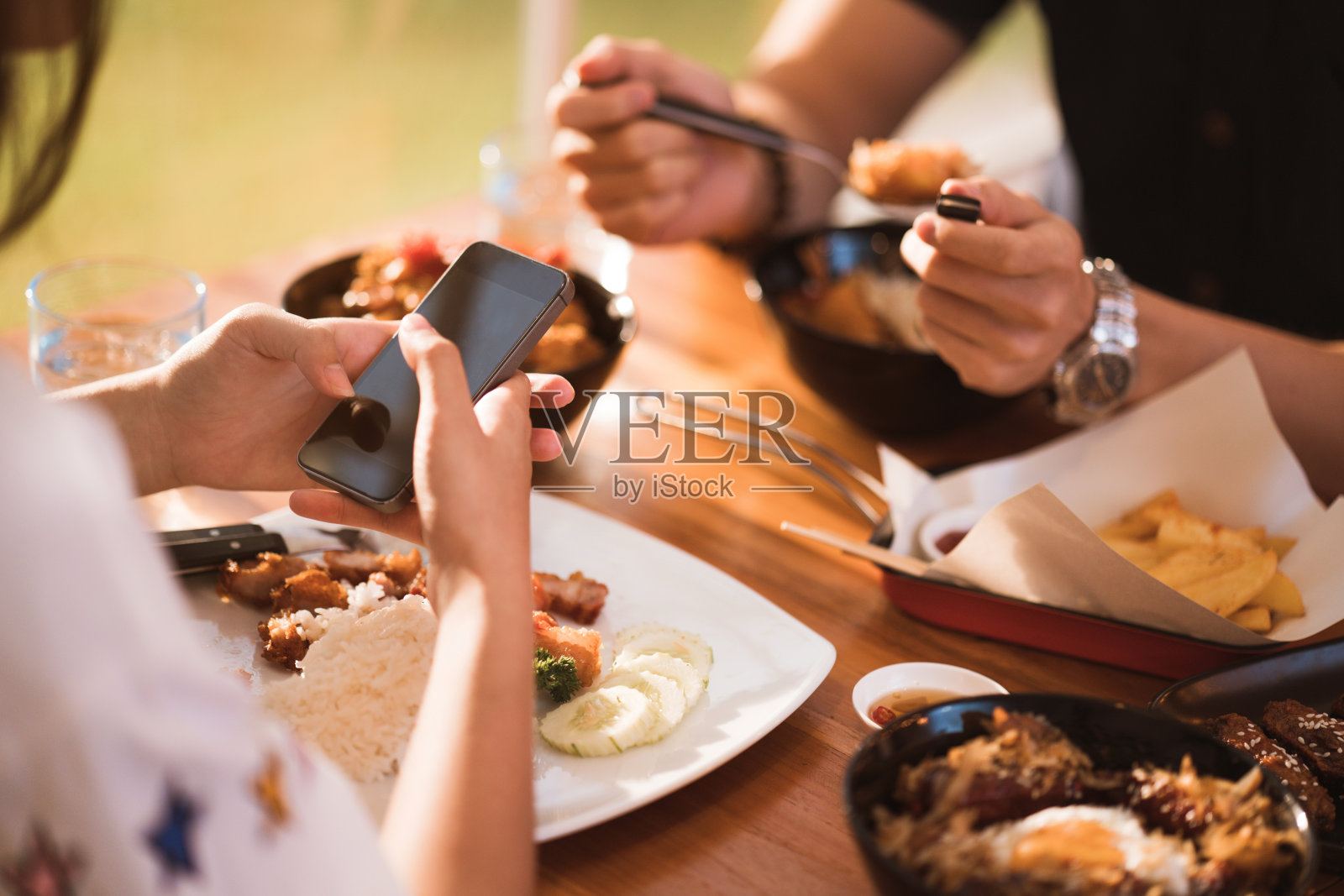 女人在餐厅和朋友吃饭时移动照片摄影图片