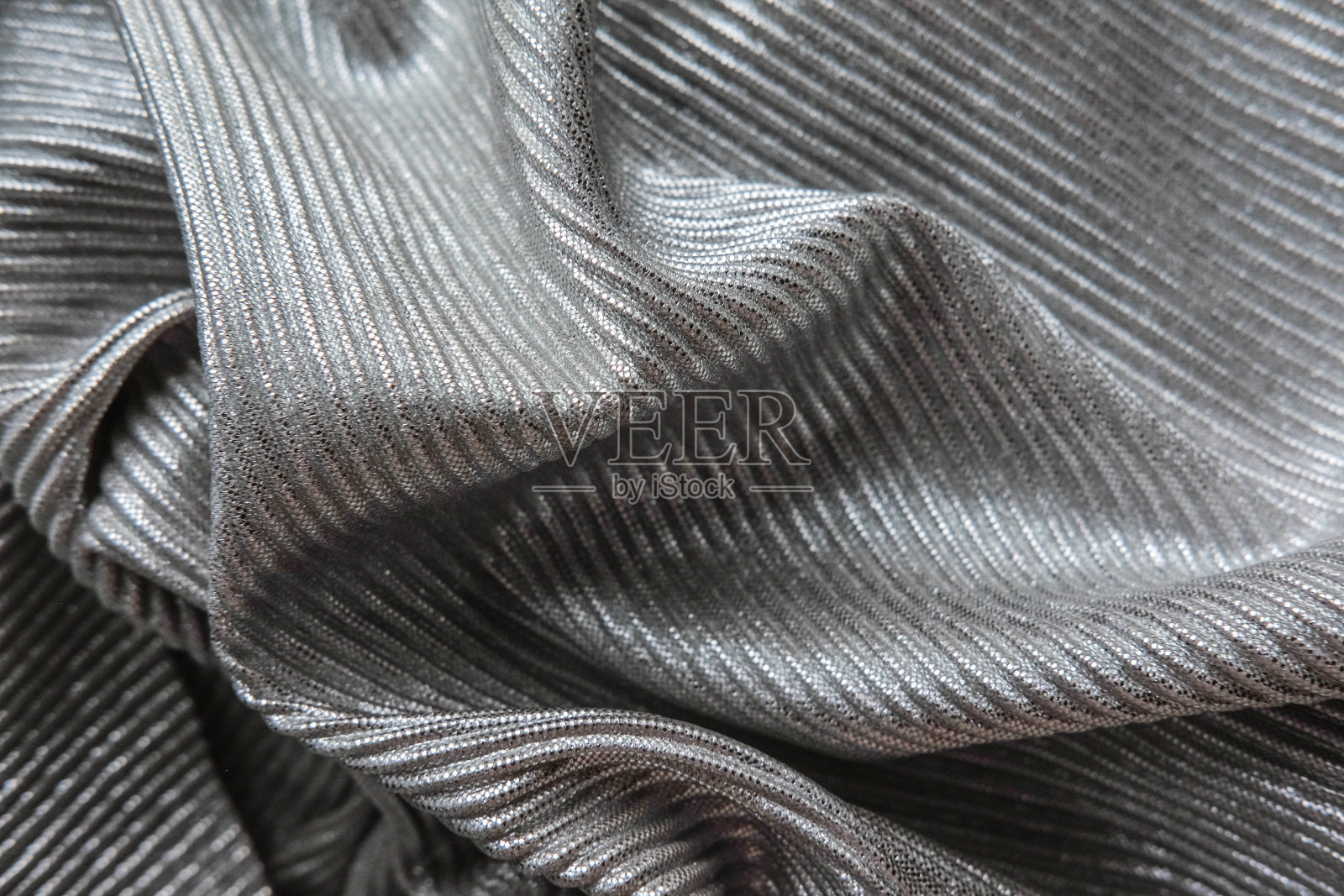 银色的织物呈波浪状排列。黑白帆布材质的纺织品。照片摄影图片