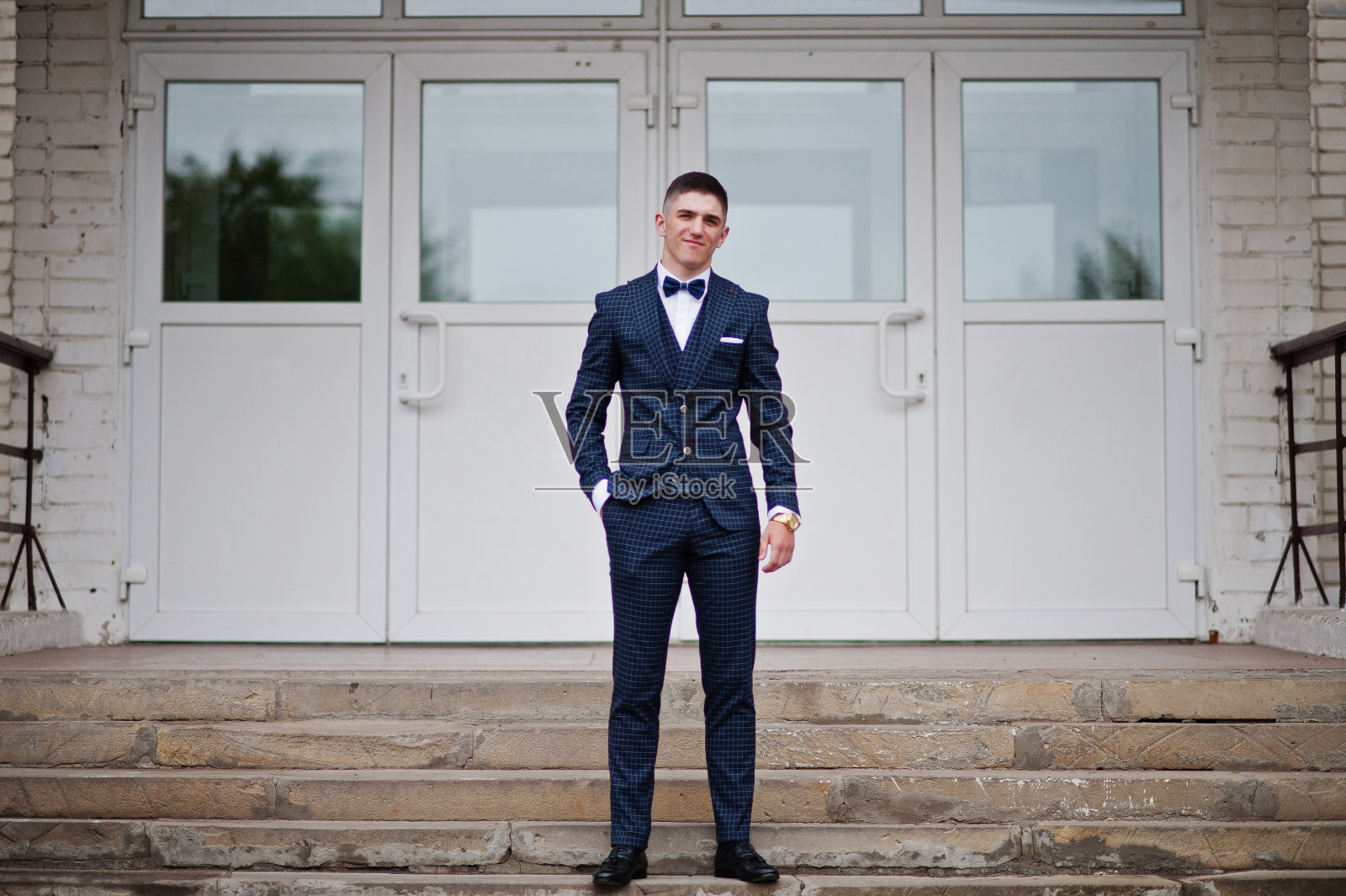 一个英俊的高中毕业生的肖像在时尚的礼服摆姿势在楼梯上的舞会。照片摄影图片
