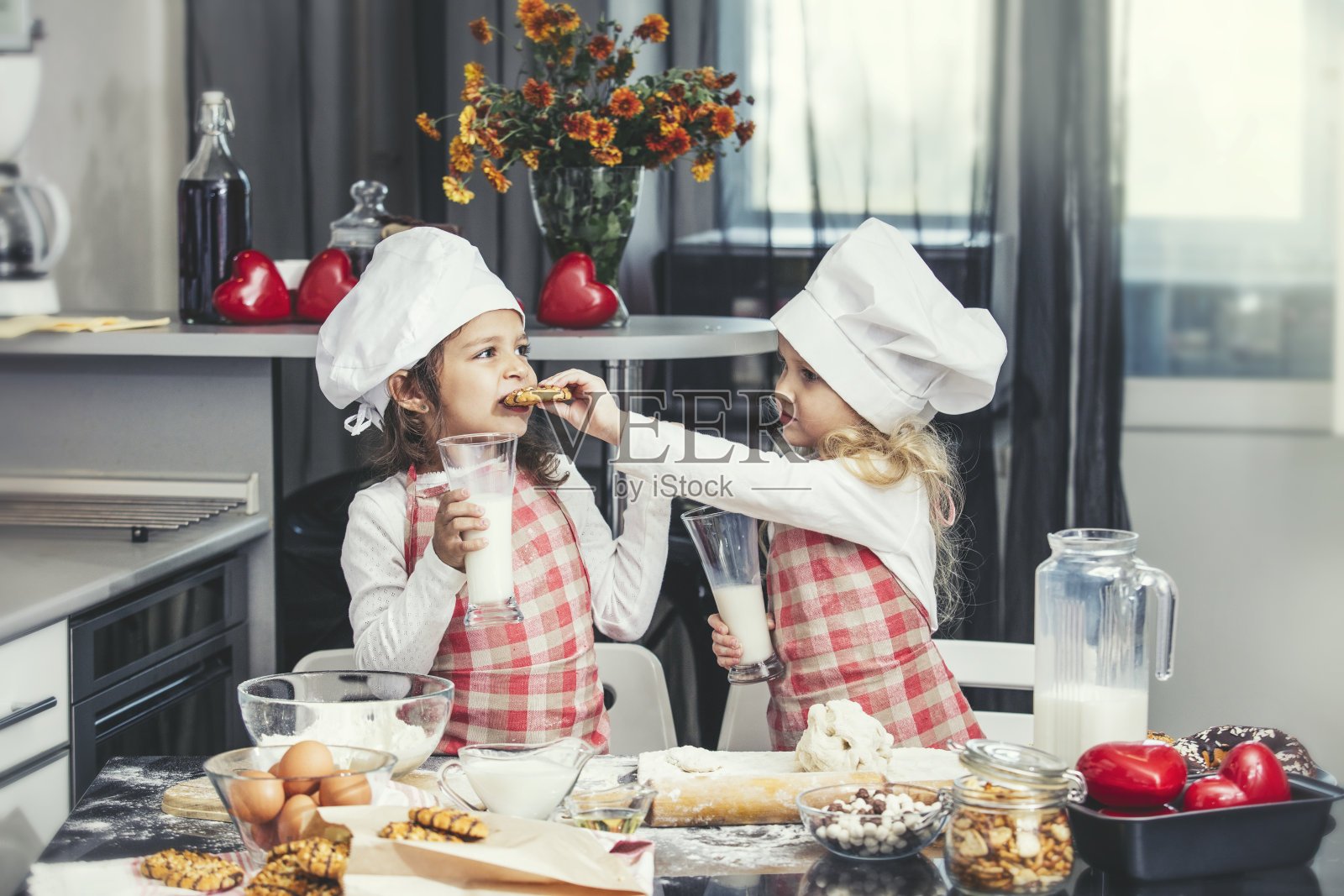 两个快乐的小女婴在厨房的餐桌上喝着牛奶做饭，可爱又美丽照片摄影图片