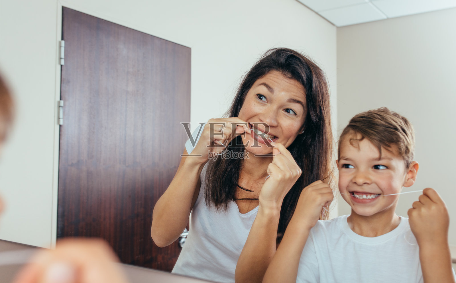 母亲和儿子用牙线清洁牙齿照片摄影图片