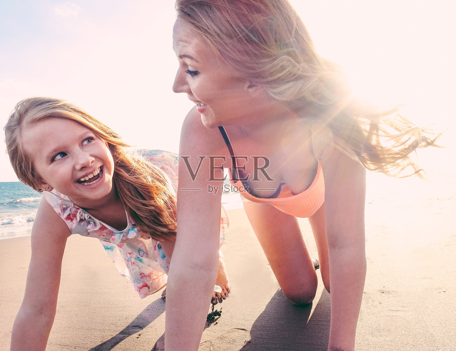 红头发的妈妈和女儿在热带海滩上玩-妈妈和她的孩子在度假-家庭生活方式和爱的概念-太阳色调滤镜-关注女人的脸照片摄影图片