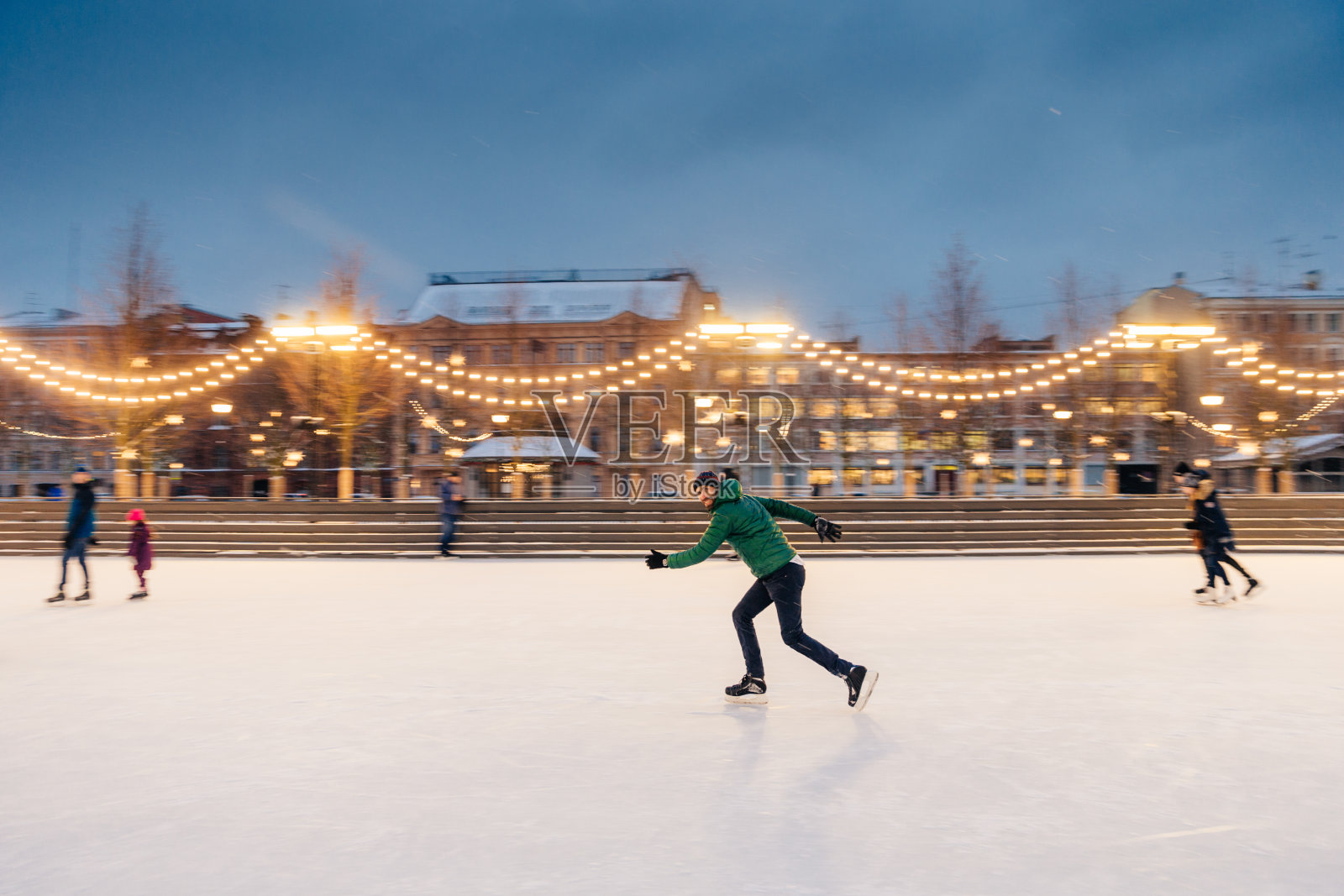 户外活跃的运动肖像胡须男性参与冬季体育活动，准备在圣诞滑冰比赛的冰环上装饰花环。积极的生活方式的概念。照片摄影图片
