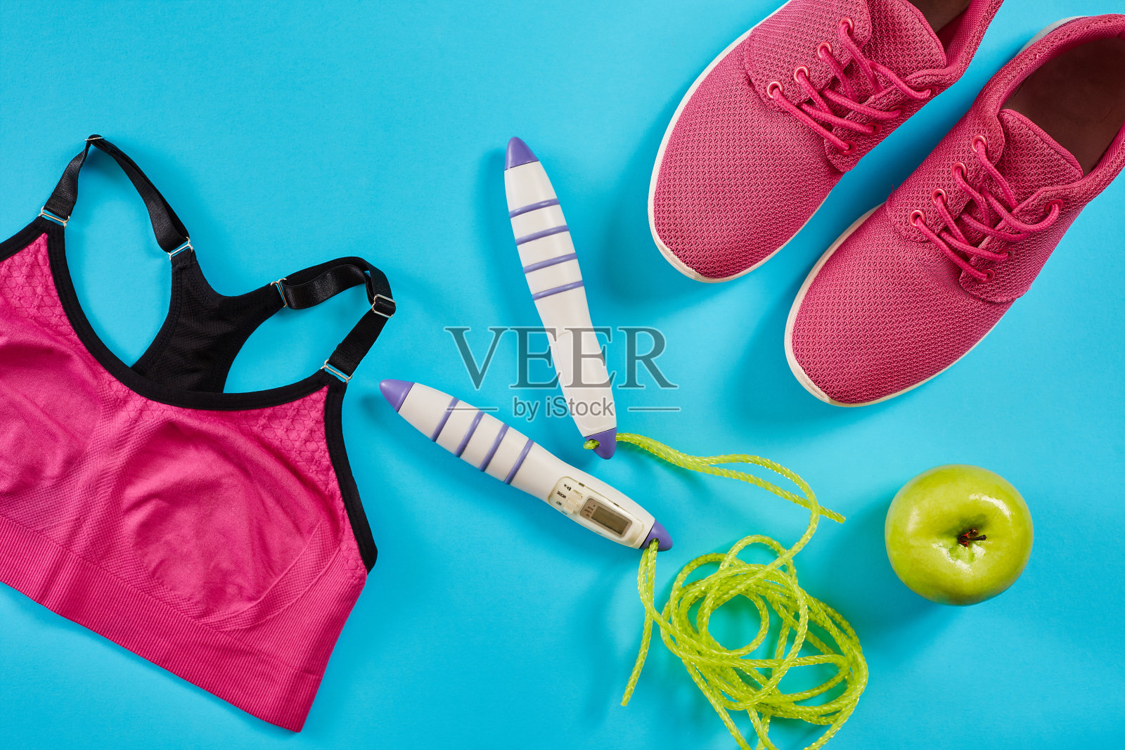 平铺的女性运动设备在粉红色与跳绳和运动鞋在蓝色的背景照片摄影图片