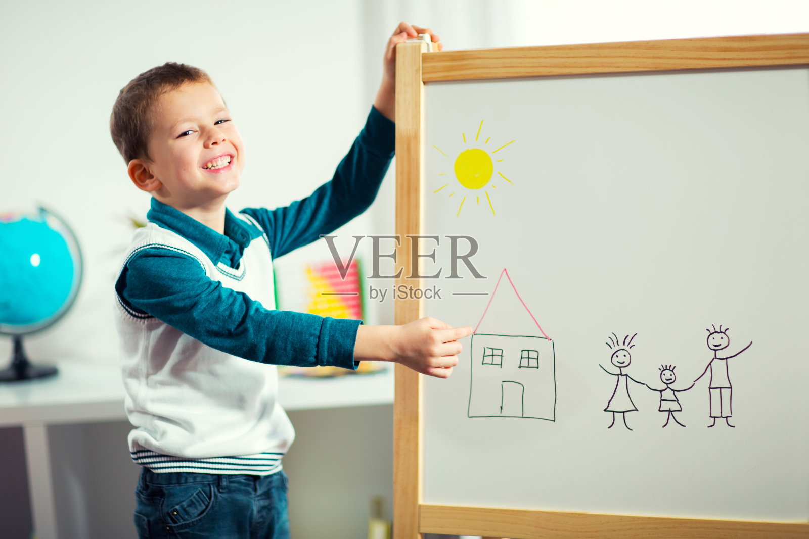可爱的小男孩微笑着用毛笔在白板上画画。照片摄影图片