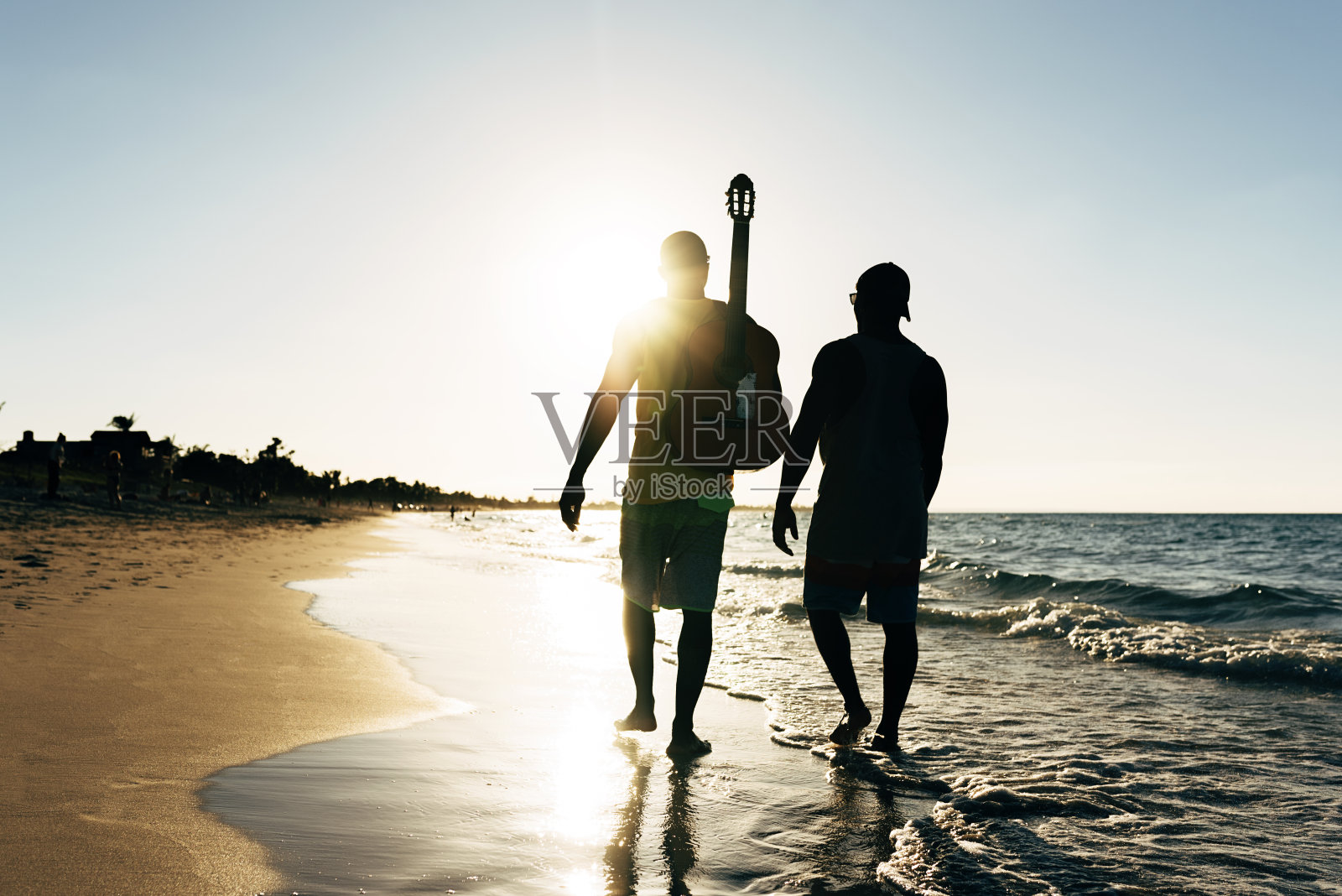 两个古巴朋友在海滩上玩他的吉他。照片摄影图片