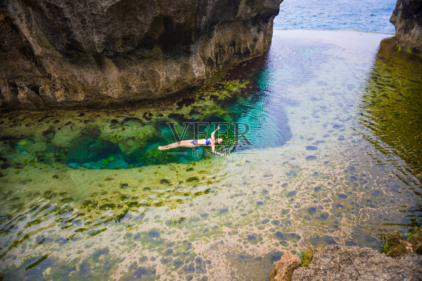 女子游泳在天使的Billabong是天然的无限游泳池，努沙佩尼达，巴厘岛照片摄影图片