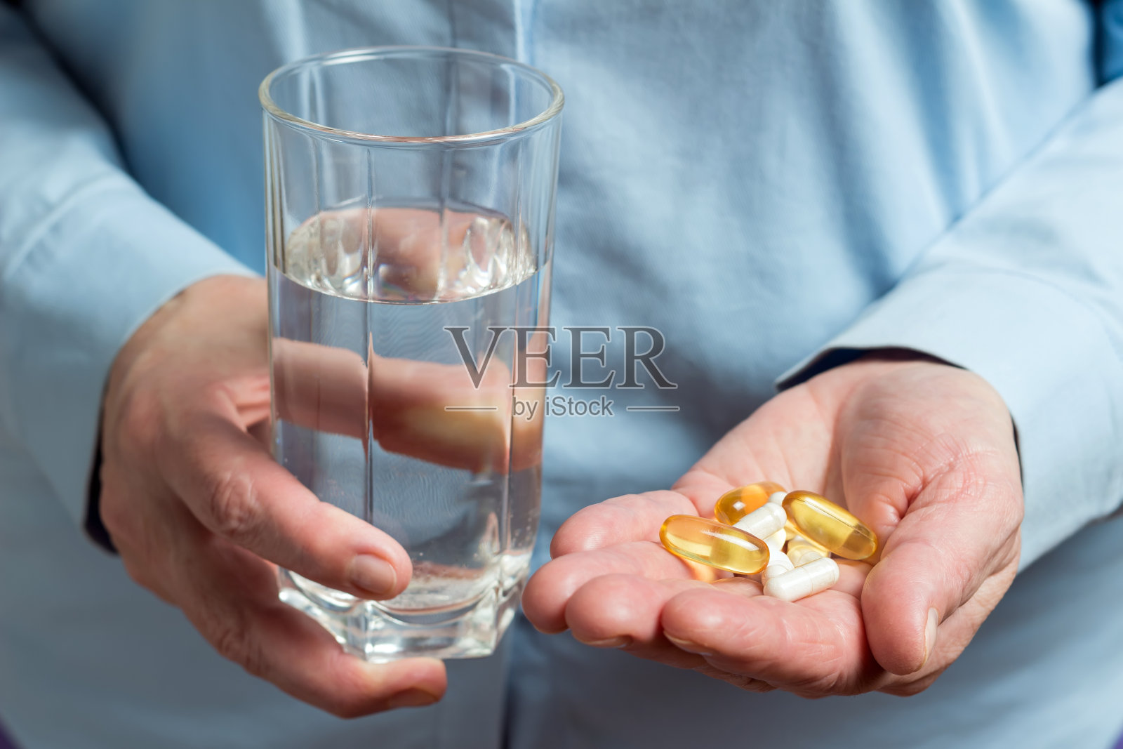 女性在手服用各种药物药丸，黄色胶囊的omega - 3，葡萄糖胺和钙膳食补充剂和玻璃与水在另一只手照片摄影图片
