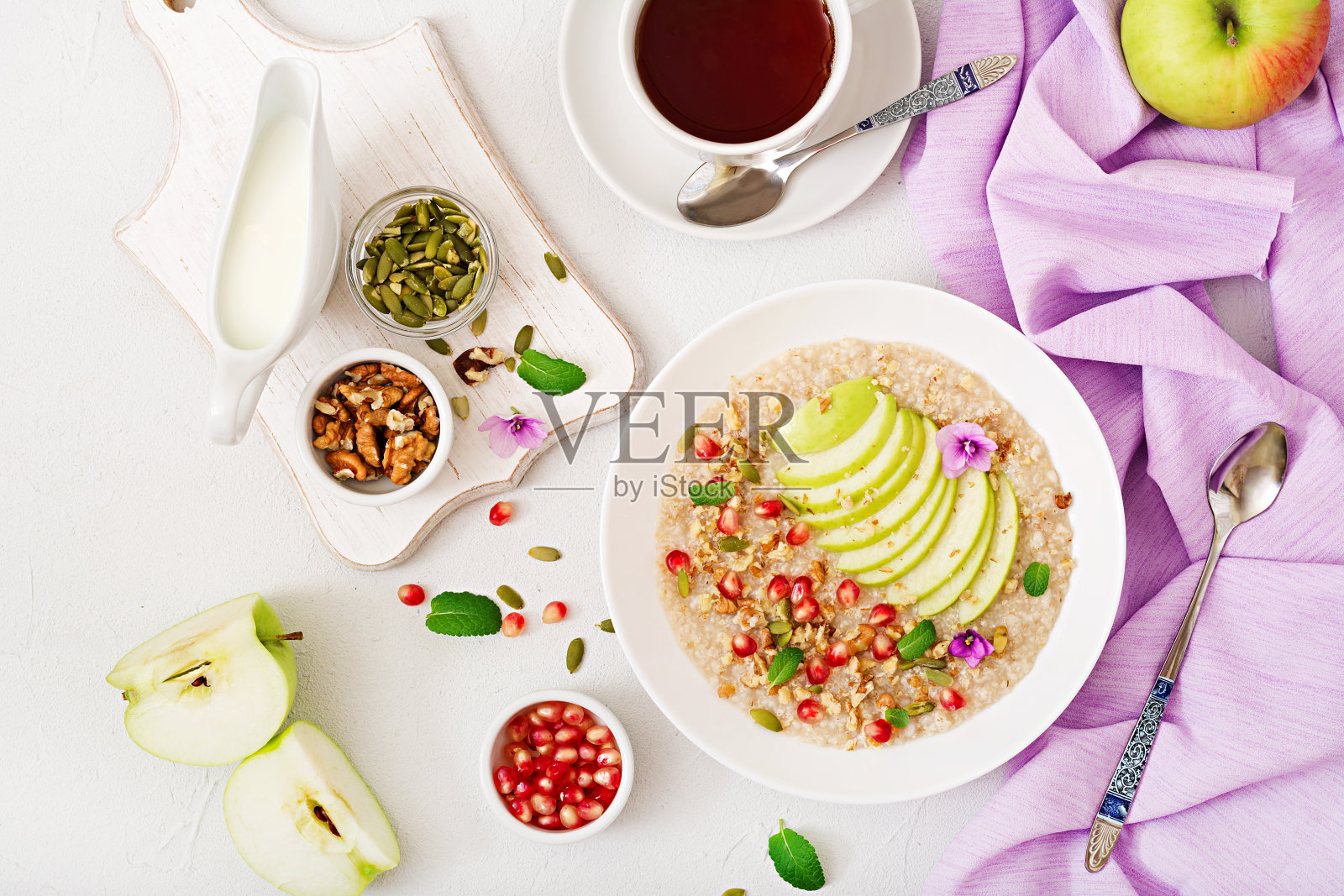 美味健康的燕麦粥，有苹果，石榴和坚果。健康的早餐。健康的食物。适当的营养。俯视图照片摄影图片