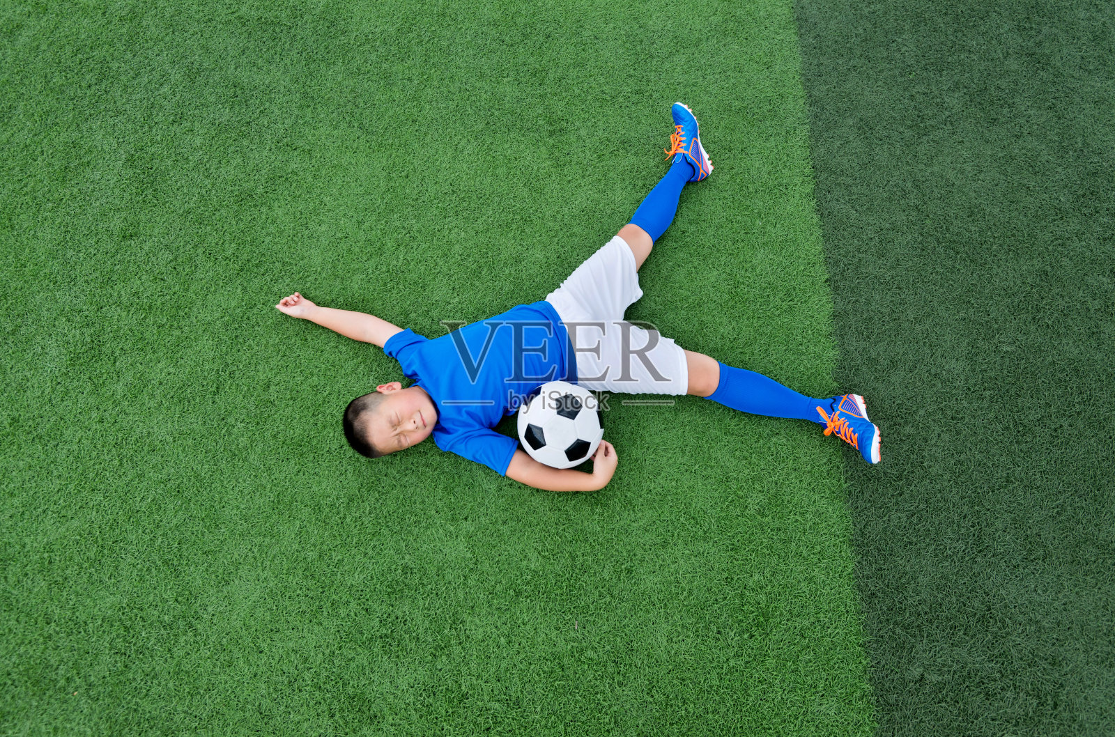 小男孩躺在足球场上照片摄影图片