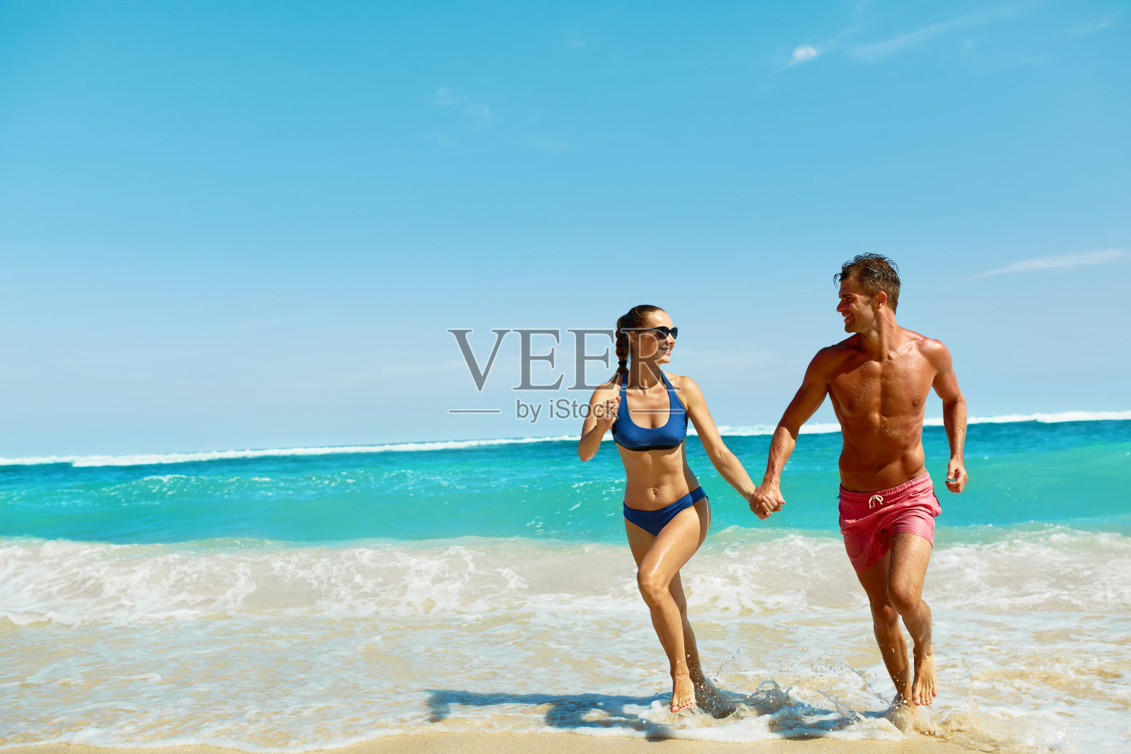 海滩上的情侣乐趣。恋爱中的浪漫的人在海上奔跑照片摄影图片