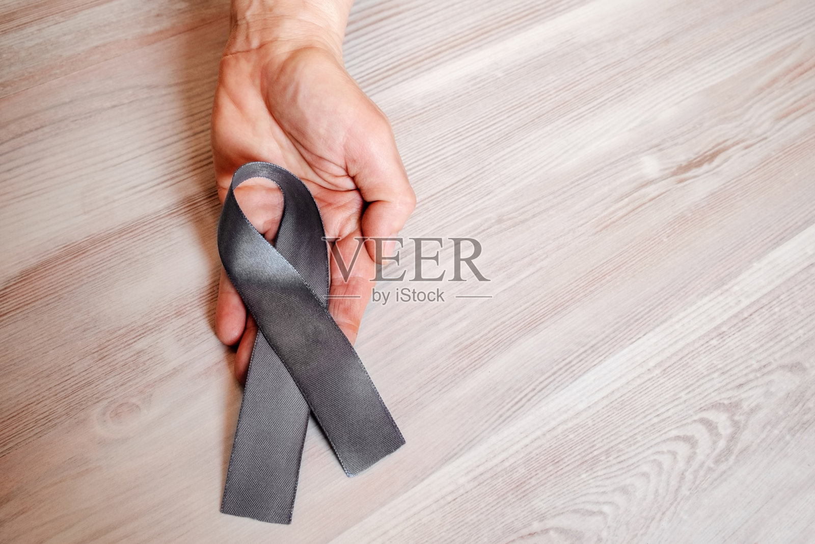 一个女人的手里拿着一条灰色的丝带。照片摄影图片