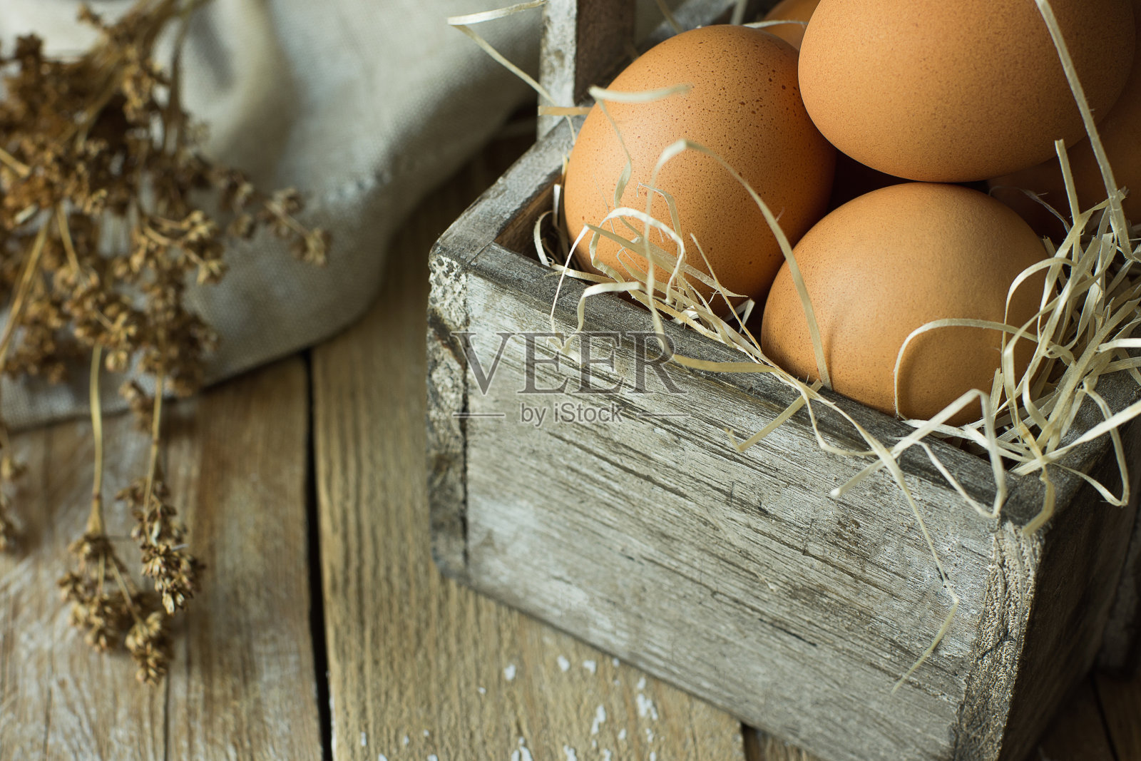 棕色有机鸡蛋在稻草上，在老式木箱上，在木板厨房桌子，亚麻餐巾，干花。复活节作品在乡村的真实风格照片摄影图片
